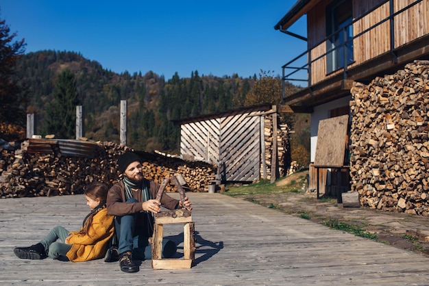 Vater und Tochter bauen zusammen ein Spielzeug-Blockhaus im Freien auf der Terrasse.