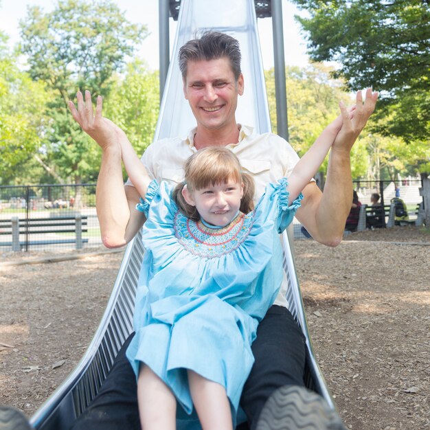 Vater und Tochter, die auf Dia am Park spielen