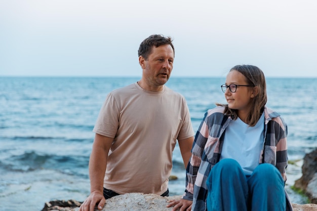 Vater und Tochter gehen an einem Sommerabend am Meer spazieren