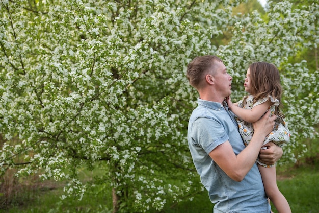 Vater und Tochter haben Spaß und spielen im Sommer im Apfelgarten