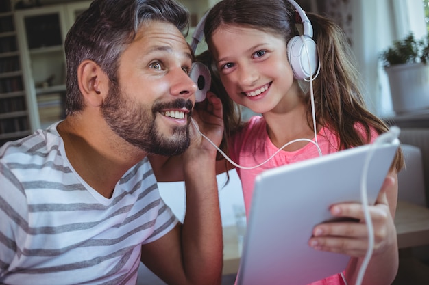 Vater und Tochter hören Musik auf digitalem Tablet