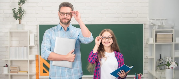 Vater und Tochter in der Schule Lehrer und Schüler Banner Glücklicher Vater und Kind lernen in der Schule mit Buch und Laptop auf Tafelhintergrund Vaterschaft