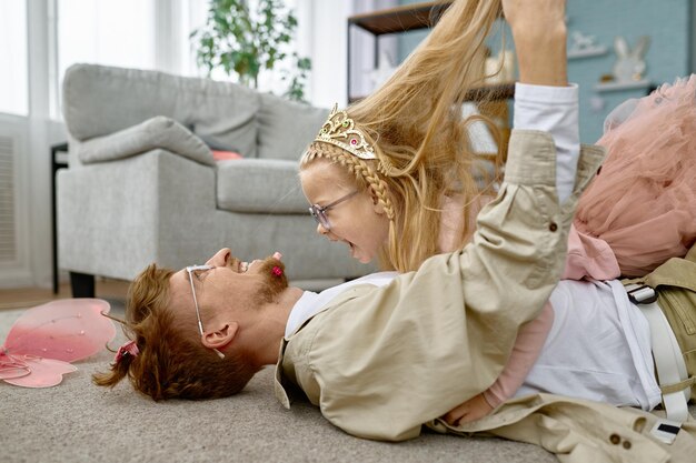 Vater und Tochter in niedlichen Kostümen haben Spaß und albern gemeinsam auf dem Boden herum