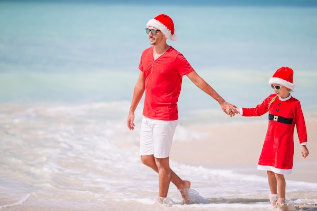 Vater und Tochter in Santa Hat haben Spaß am tropischen Strand