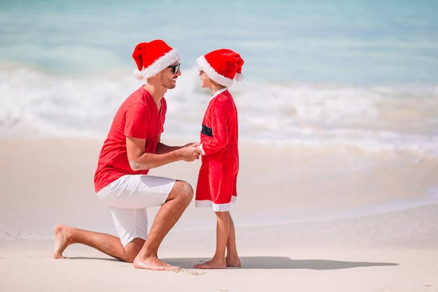 Vater und Tochter in Santa Hat haben Spaß am tropischen Strand