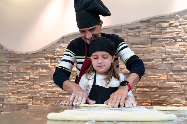 Foto vater und tochter kochen gemeinsam ein gebäck in kochkostümen