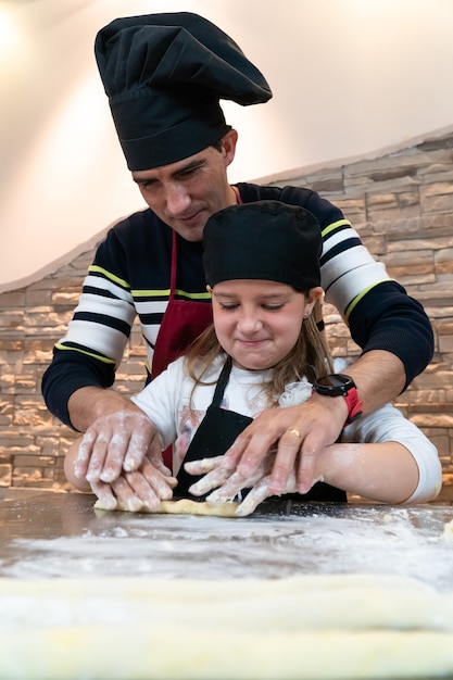 Foto vater und tochter kochen gemeinsam ein gebäck in kochkostümen