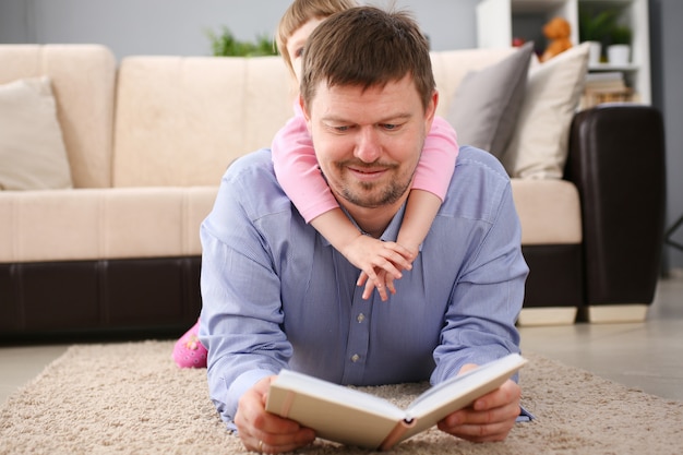 Vater und Tochter liegen auf dem Boden und lesen ein interessantes Buch