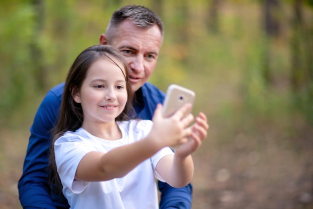 Vater und Tochter machen Selfie auf dem Smartphone im Freien