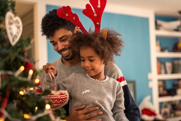 Vater und Tochter schmücken gemeinsam den Weihnachtsbaum