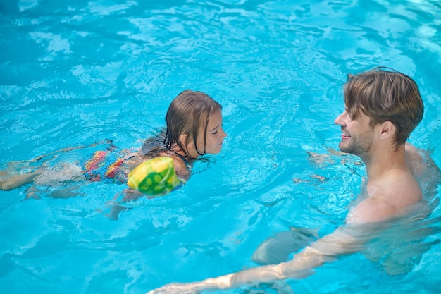 Vater und Tochter schwimmen zusammen in einem Schwimmbad