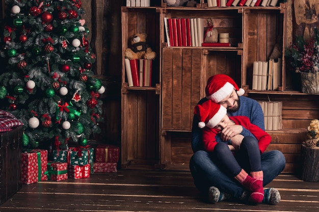 Vater und Tochter sitzen auf dem Boden, umarmen sich und warten auf Weihnachten