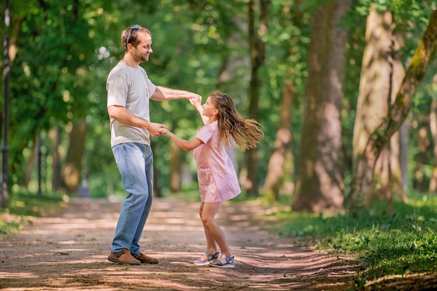 Vater und Tochter spielen im Park tanzen. Glückliches Familienkonzept. Schönheitsnaturszene mit Lebensstil im Freien der Familie. Glückliche Familie, die zusammen ruht. Glück und Harmonie im Familienleben.