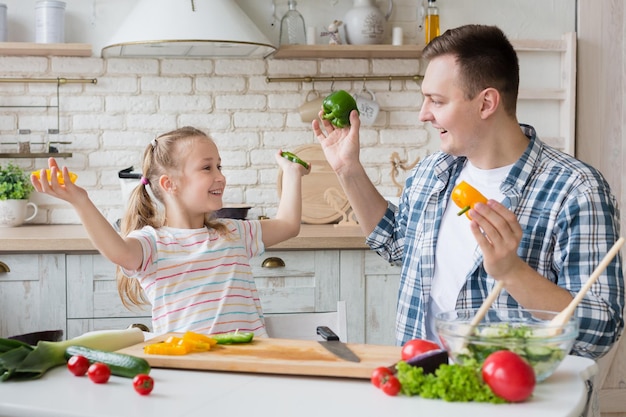 Vater und Tochter spielen mit Pfefferscheiben beim gemeinsamen Kochen in der Küche, Kopierraum