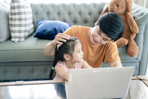 Vater und Tochter spielen zu Hause mit Notebook-Computer