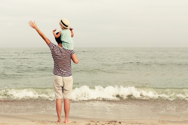 Vater und Tochter stehen am Strand und schauen auf das Meer