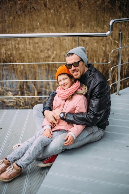 Vater und Tochter umarmen sich, haben Spaß und lachen draußen im Herbst