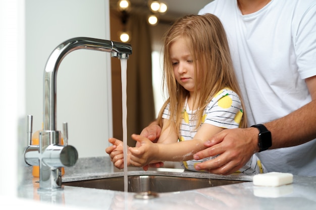 Vater und Tochter waschen ihre Hände über dem Waschbecken in einer Küche