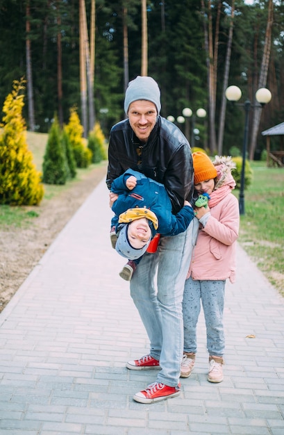 Vater und zwei Kinder gehen im Herbst in der Natur spazieren, verbringen Zeit miteinander und haben Spaß