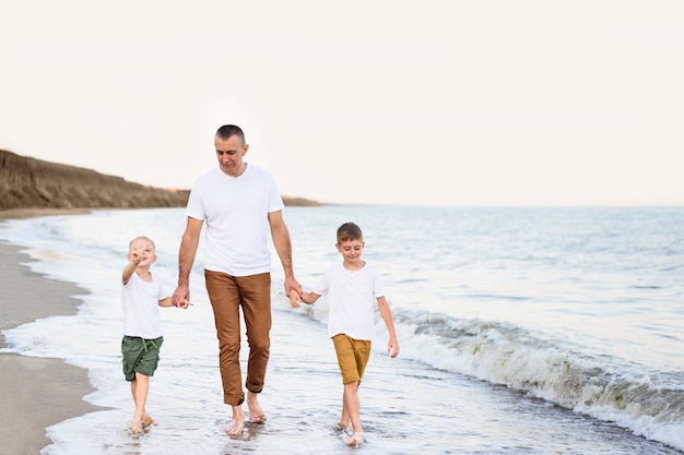Vater und zwei Söhne gehen die Küste entlang. Urlaub genießen