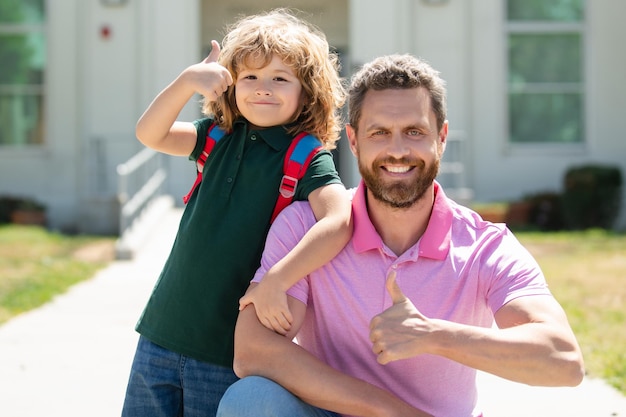 Vater unterstützt und motiviert Sohn Kind mit Daumen nach oben zur Grundschule zurück zur Schule