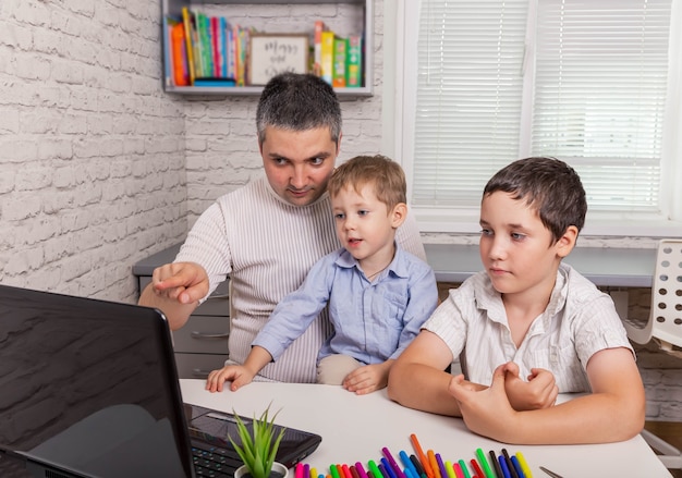 Vater versucht, am Laptop mit dem Arzt zu sprechen, während die Kinder zu Hause bleiben