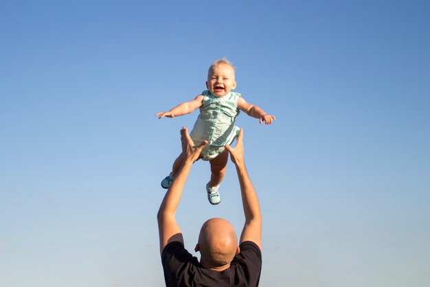 Vater wirft sein Kind gegen den blauen Himmel
