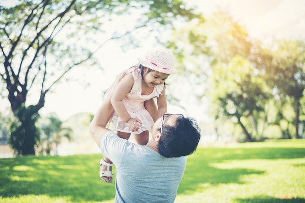 Vater wirft seine Tochter hoch gegen, glückliche Zeitfamilie.