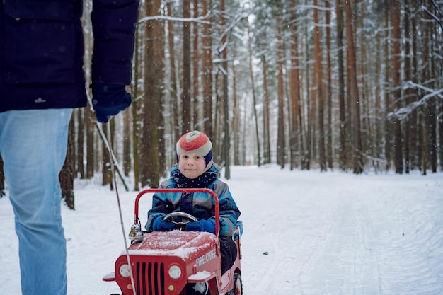 Vater zieht am Seil Kinderauto mit kleinem Sohn, der darin sitzt