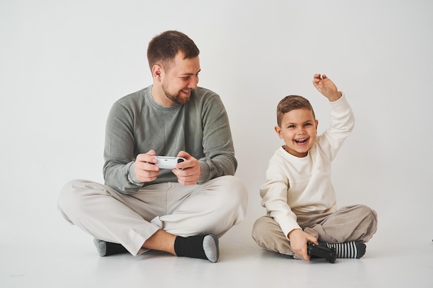 Vaterschaft Vater und Sohn spielen Gamepad-Konsolenspiel, lachen und haben Spaß zusammen Gamer spielen Computerspiele