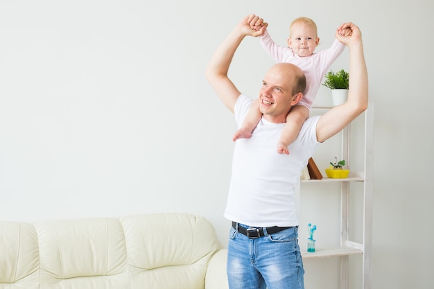 Vaterschafts- und Familienkonzept - Vater und kleines Kleinkindbaby drinnen zu Hause, spielend.