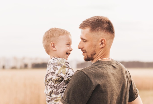 Vatertag Glücklicher Familienvater und kleiner Sohn, der bei Sonnenuntergang in der Natur spielt und lacht