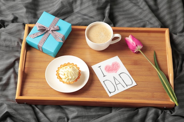 Vatertagskonzept mit Geschenk und Frühstück auf Tablett Frühstück für Papa mit Croissant und Kaffee