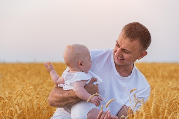 Vati, der das kleine Kind hält, das im Bereich des reifen Weizens steht Junger Vater und Baby Zärtlichkeit