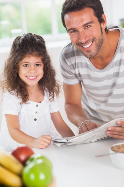 Vati und Tochter, die eine Zeitung während des Frühstücks in der Küche lesen