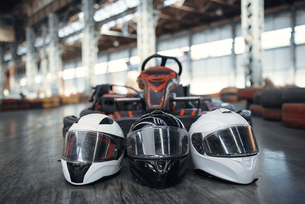 Vaya coche kart y cascos en el suelo, karting auto sport indoor. Pista de karts de carreras de velocidad. Competencia de vehículos rápidos, persecución