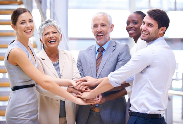 Vaya equipo Disparo de un grupo de compañeros de trabajo sonrientes con las manos apiladas