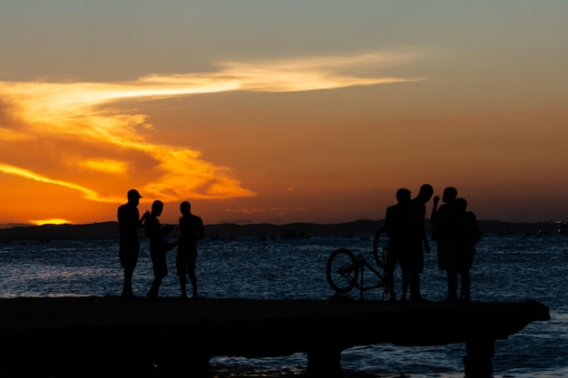 Se ve a jóvenes en silueta disfrutando juntos de la puesta de sol desde la parte superior del puente Crush en la ciudad de Salvador Bahia