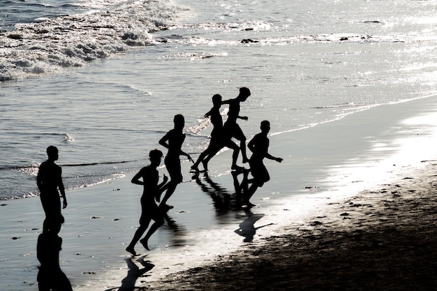 Se ve a jóvenes en silueta jugando al fútbol de playa en la playa de Ondina en Salvador Bahia