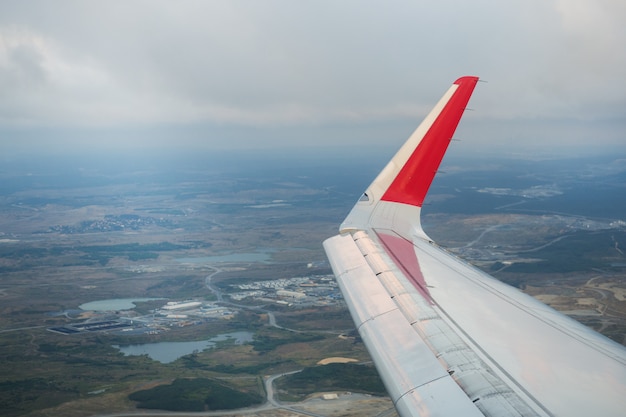 Foto vea el ala del avión de pasajeros y el suelo desde la ventana del avión volador.