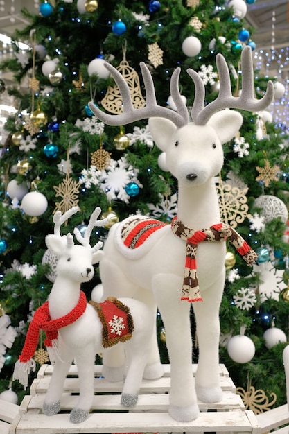 Veado de Natal branco e veado pequeno perto da árvore de Natal. Rudolf veado. Composição de natal