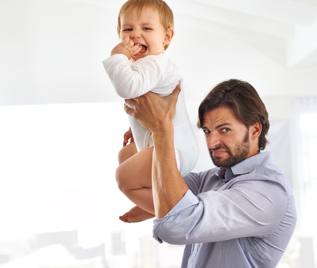 A veces puede ser un trabajo sucio Foto de un apuesto padre sosteniendo a su hijo en el aire mientras hace una mueca