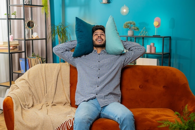 Los vecinos en el trabajo de reparación irritaron al hombre por la música fuerte en casa cubren las orejas con almohadas molestadas por el ruido