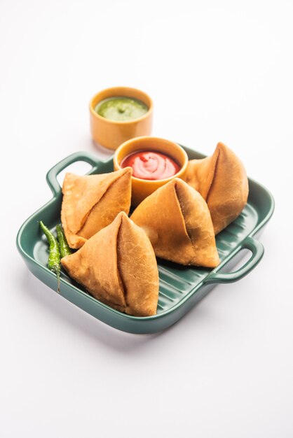 Veg Samosa - é um lanche crocante e picante em forma de triângulo indiano que tem uma camada externa crocante de maida e recheio de purê de batata, ervilhas e especiarias