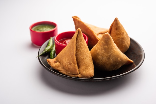 Veg Samosa - é um lanche crocante e picante em forma de triângulo indiano que tem uma camada externa crocante de maida e recheio de purê de batata, ervilhas e especiarias