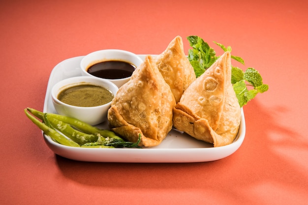 Veg Samosa é um lanche popular indiano ou junk food servido com pimenta verde frita, cebola e chutney ou ketchup