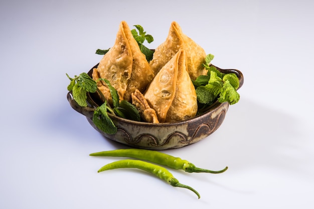 Veg Samosa é um lanche popular indiano ou junk food servido com pimenta verde frita, cebola e chutney ou ketchup