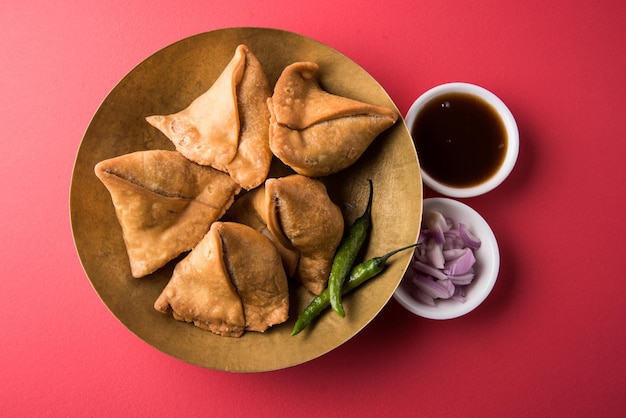 Veg Samosa: es un bocadillo indio crujiente y picante en forma de triángulo que se sirve a la hora del té, servido con salsa verde frita, cebolla y chutney o ketchup.