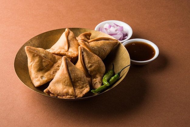 Veg Samosa: es un bocadillo indio crujiente y picante en forma de triángulo que se sirve a la hora del té, servido con salsa verde frita, cebolla y chutney o ketchup.