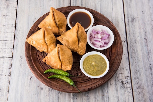 Veg samosa - ist ein knuspriger und würziger indischer tea time snack in dreiecksform, serviert mit gebratenem grünem chili, zwiebeln & chutney oder ketchup